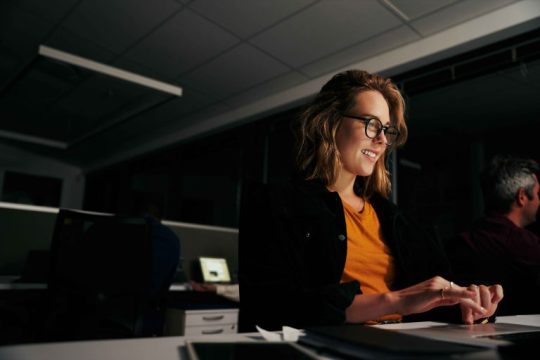 Girl writing on a laptop wearing an orange shirt and glasses